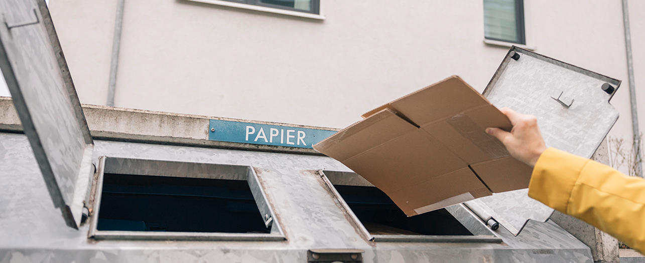 Person recycling cardboard into a paper waste container Person recycling cardboard into a paper waste container
